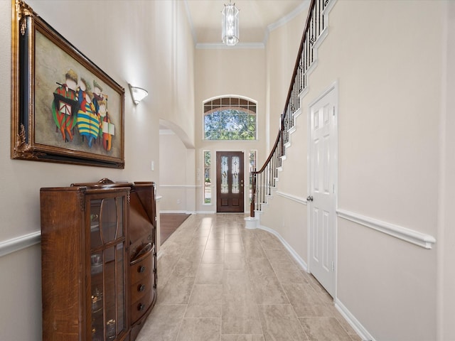 foyer with a towering ceiling, crown molding, and an inviting chandelier