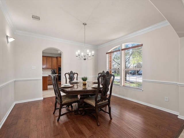 dining space featuring dark hardwood / wood-style floors, an inviting chandelier, and ornamental molding