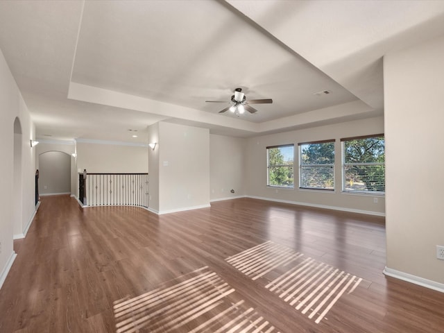 spare room with ceiling fan, dark hardwood / wood-style flooring, and a tray ceiling