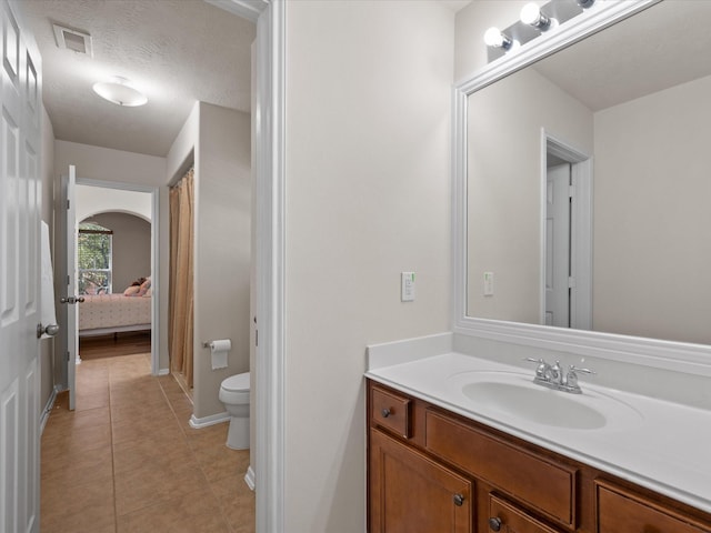 bathroom with tile patterned flooring, vanity, toilet, and a textured ceiling