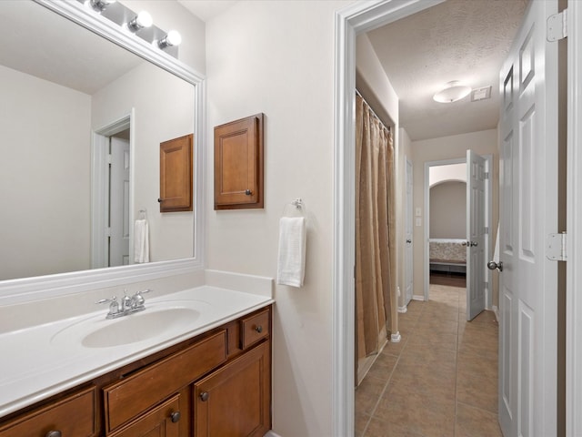 bathroom with tile patterned floors, vanity, and a textured ceiling