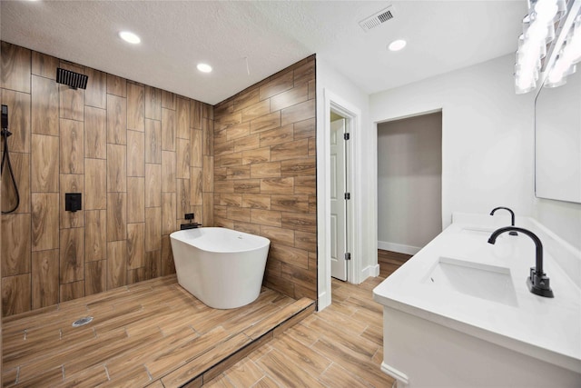 bathroom featuring separate shower and tub, wood walls, vanity, and a textured ceiling