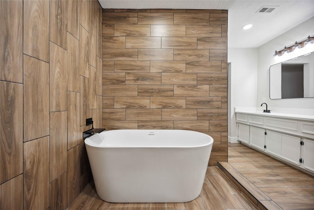 bathroom with vanity, a bathtub, and tile walls