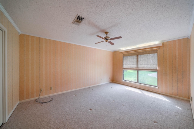 spare room featuring a textured ceiling, light colored carpet, ceiling fan, and crown molding