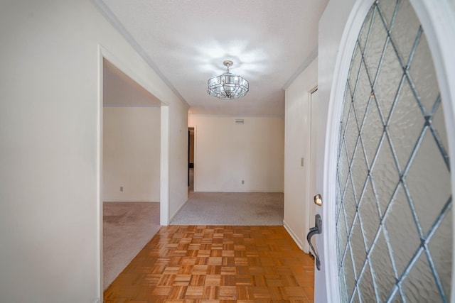 interior space with light carpet, ornamental molding, a textured ceiling, and an inviting chandelier