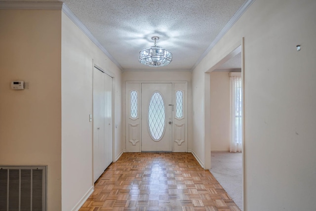 entryway with a chandelier, a textured ceiling, and ornamental molding