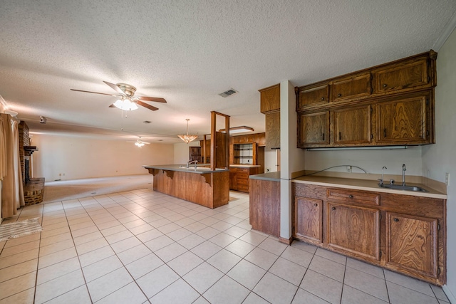 kitchen featuring sink, hanging light fixtures, ceiling fan, light tile patterned flooring, and a kitchen bar