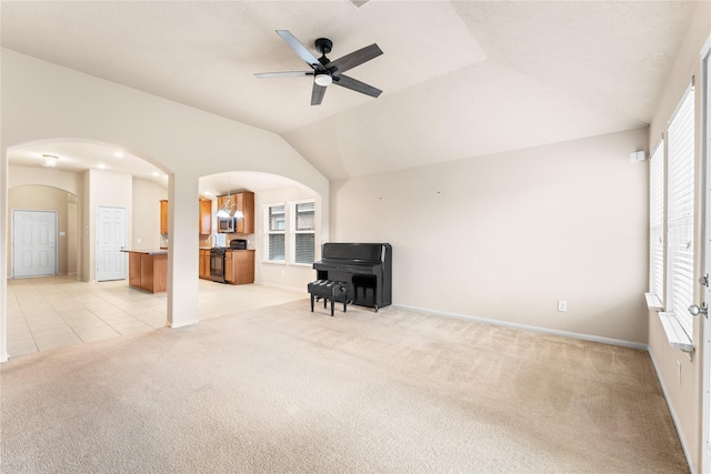 carpeted living room with ceiling fan with notable chandelier and lofted ceiling