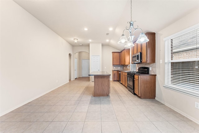 kitchen with pendant lighting, a center island, lofted ceiling, an inviting chandelier, and gas stove