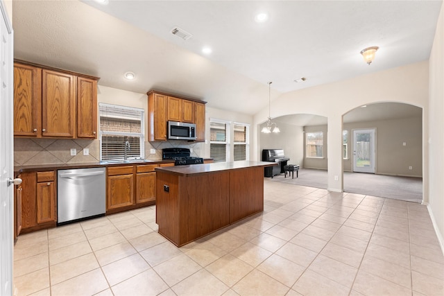 kitchen with appliances with stainless steel finishes, tasteful backsplash, a notable chandelier, a kitchen island, and hanging light fixtures