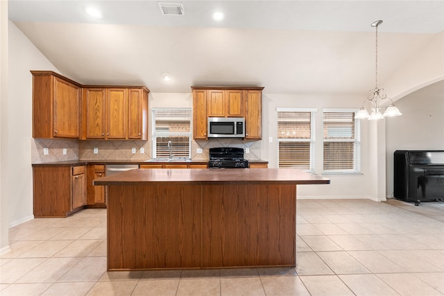 kitchen with lofted ceiling, an inviting chandelier, sink, light tile patterned floors, and appliances with stainless steel finishes