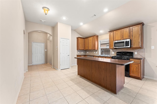 kitchen with a center island, lofted ceiling, sink, decorative backsplash, and gas stove