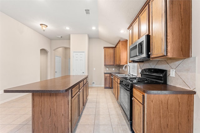 kitchen with light tile patterned flooring, sink, a kitchen island, and stainless steel appliances