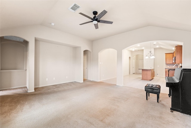 unfurnished living room with light carpet, ceiling fan with notable chandelier, and lofted ceiling