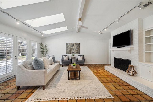 living room with a fireplace, tile patterned flooring, lofted ceiling with skylight, and ceiling fan