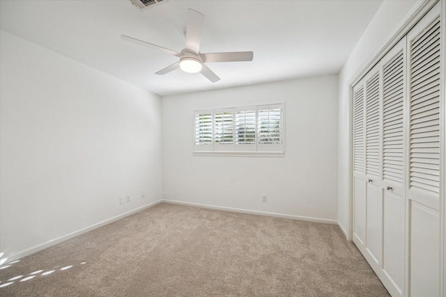 unfurnished bedroom with ceiling fan, light colored carpet, and a closet