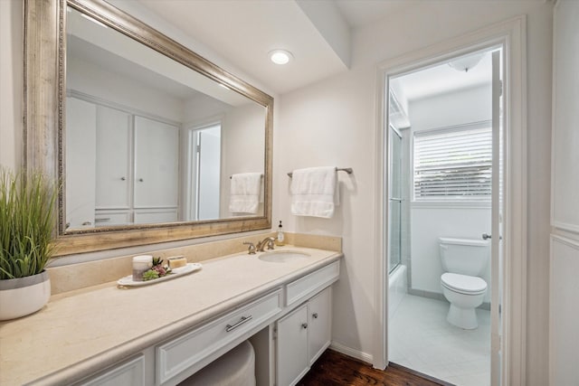 full bathroom with hardwood / wood-style flooring, vanity, bath / shower combo with glass door, and toilet