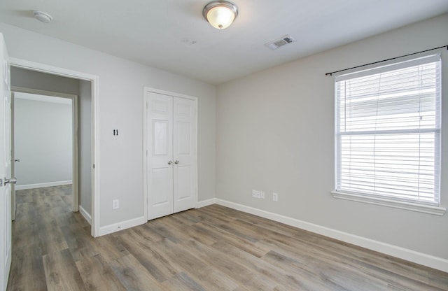 unfurnished bedroom featuring hardwood / wood-style floors and a closet