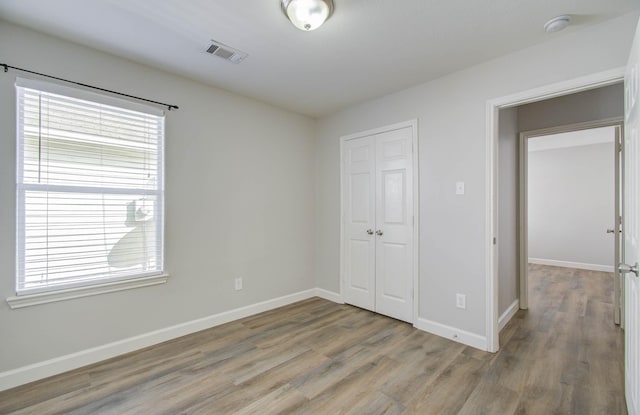 unfurnished bedroom featuring a closet, light hardwood / wood-style flooring, and multiple windows