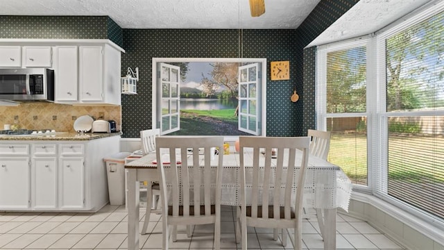 dining area featuring ceiling fan, light tile patterned floors, and a textured ceiling