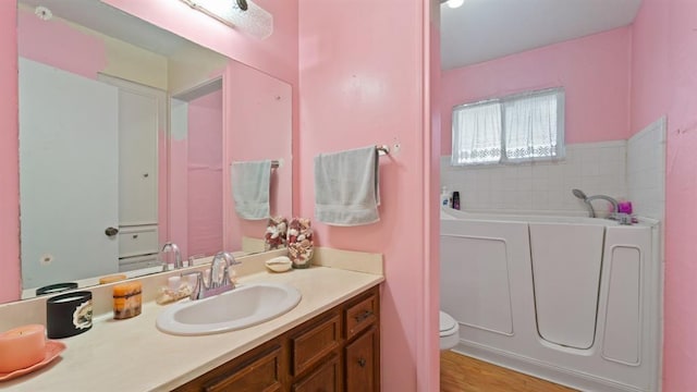 bathroom featuring a tub, hardwood / wood-style flooring, vanity, and toilet