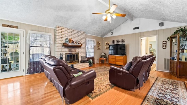 living room featuring plenty of natural light, ceiling fan, light hardwood / wood-style flooring, and a brick fireplace