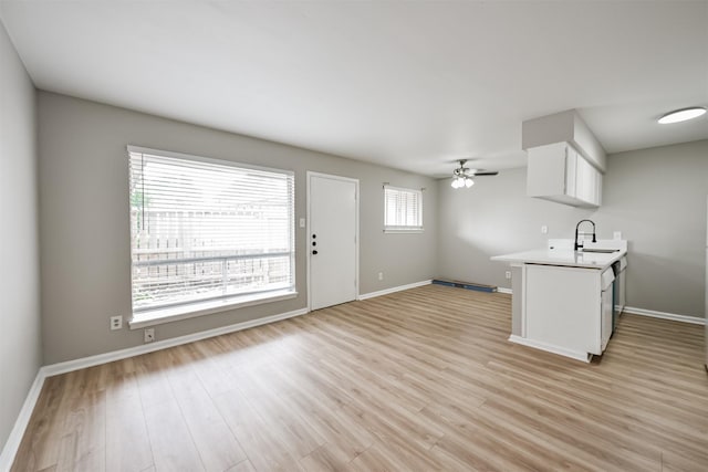 kitchen featuring ceiling fan, white cabinetry, kitchen peninsula, and light hardwood / wood-style flooring