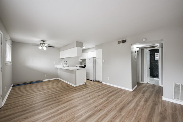 kitchen featuring white cabinets, light hardwood / wood-style flooring, ceiling fan, white fridge, and kitchen peninsula