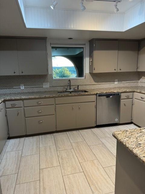 kitchen featuring track lighting, stainless steel dishwasher, gray cabinetry, and sink