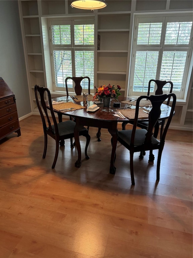 dining space with built in shelves and wood finished floors