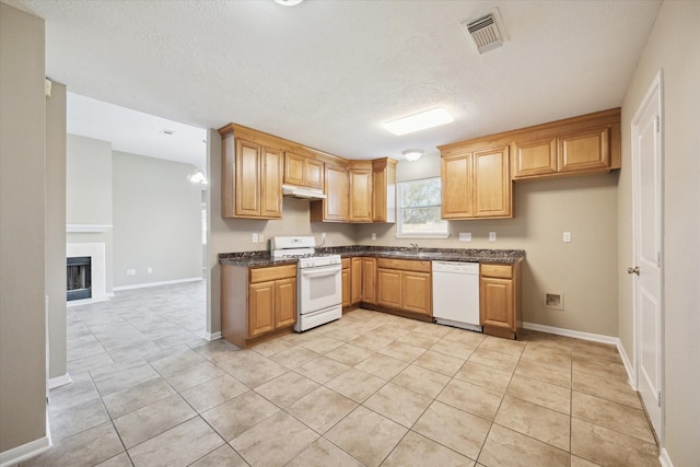 kitchen with a textured ceiling, sink, light tile patterned flooring, and white appliances