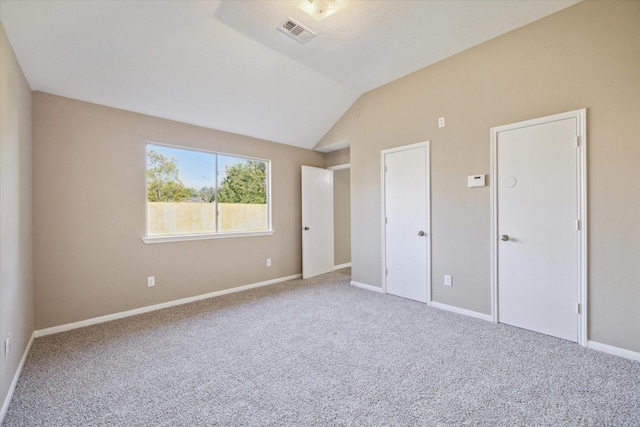 unfurnished bedroom featuring carpet and lofted ceiling