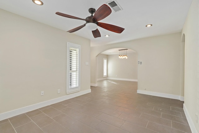 empty room featuring ceiling fan with notable chandelier and light tile patterned floors