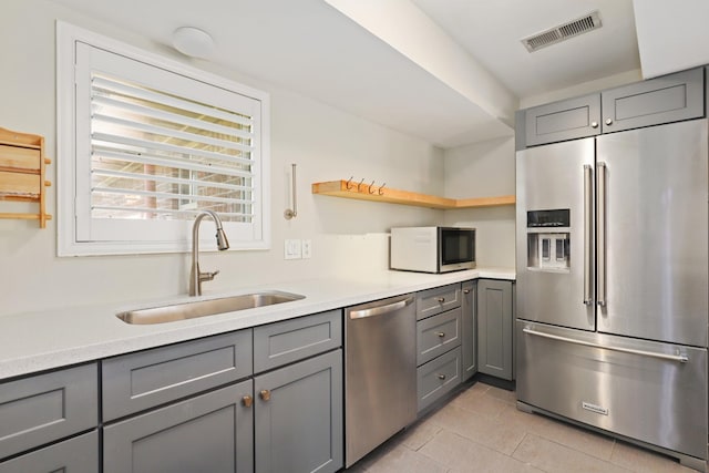 kitchen with gray cabinets, sink, light tile patterned floors, and stainless steel appliances