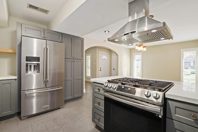 kitchen with island exhaust hood, appliances with stainless steel finishes, gray cabinets, and a wealth of natural light