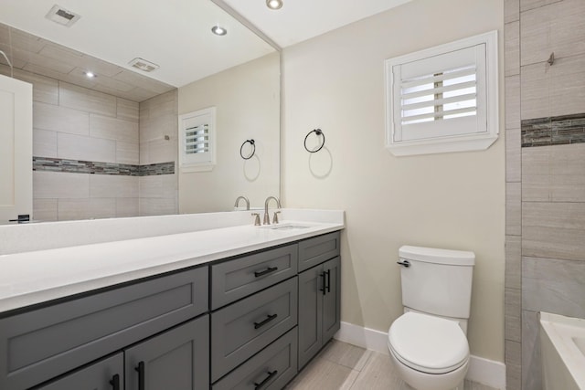 bathroom with tile patterned flooring, a tile shower, vanity, and toilet