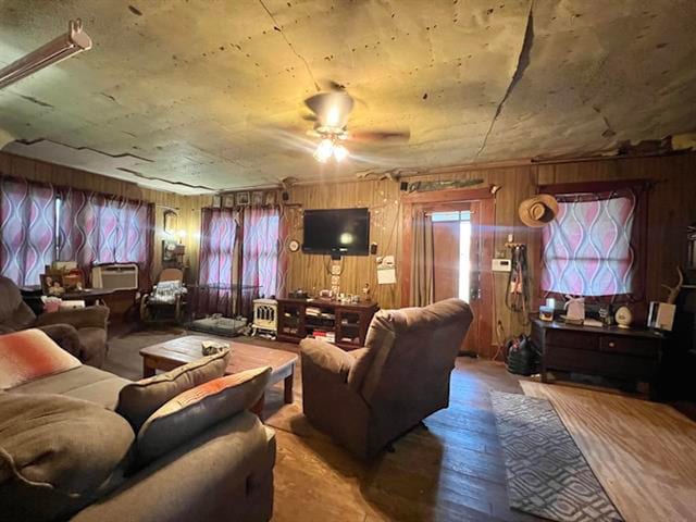 living room featuring ceiling fan, wooden walls, and hardwood / wood-style floors