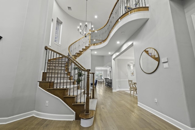 entryway with a high ceiling, an inviting chandelier, and wood-type flooring