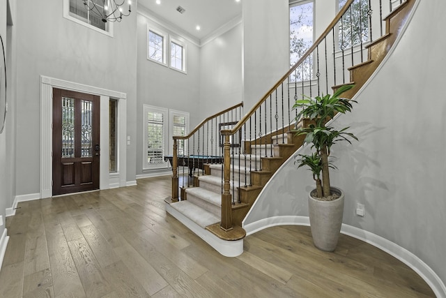 entryway featuring a healthy amount of sunlight, a high ceiling, light wood-type flooring, an inviting chandelier, and ornamental molding