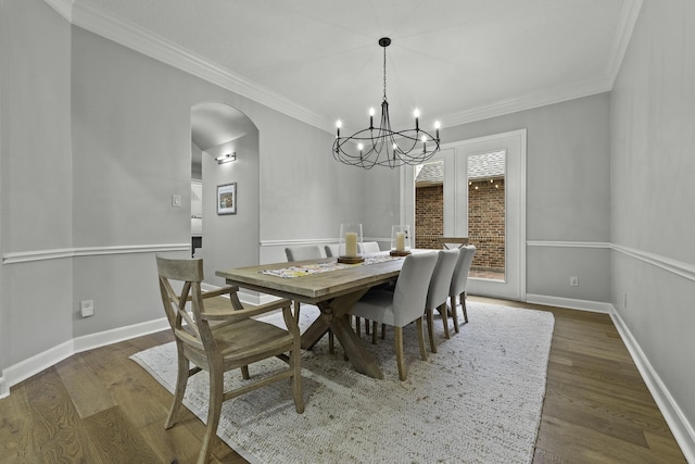 dining area featuring dark wood-type flooring, ornamental molding, and a chandelier