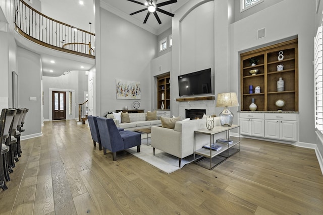 living room featuring ceiling fan, crown molding, a towering ceiling, and wood-type flooring