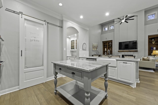 kitchen with a kitchen island, a barn door, white cabinetry, ceiling fan, and sink