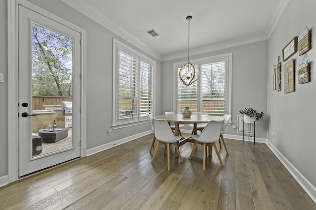 dining room with ornamental molding, an inviting chandelier, and wood-type flooring