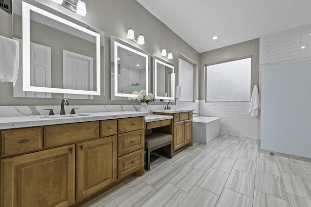 bathroom with tile walls, vanity, and shower with separate bathtub