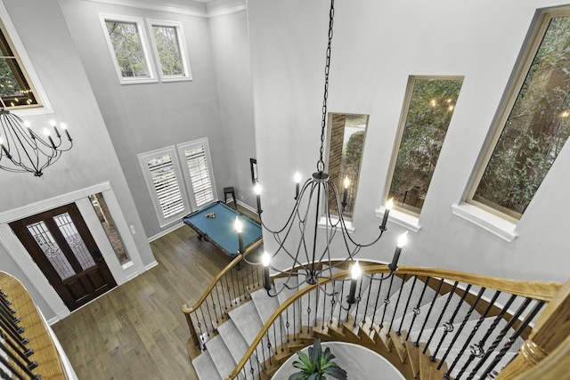 entrance foyer with a towering ceiling, a chandelier, hardwood / wood-style floors, and crown molding