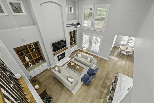 living room with ceiling fan, wood-type flooring, and a high ceiling