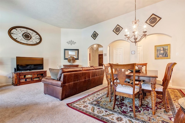 carpeted dining area with a notable chandelier and a towering ceiling