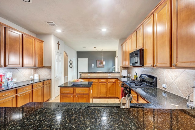 kitchen featuring decorative backsplash, sink, black appliances, pendant lighting, and dark stone countertops