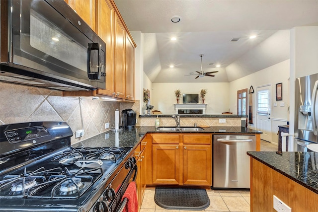 kitchen featuring dark stone counters, sink, black appliances, and vaulted ceiling