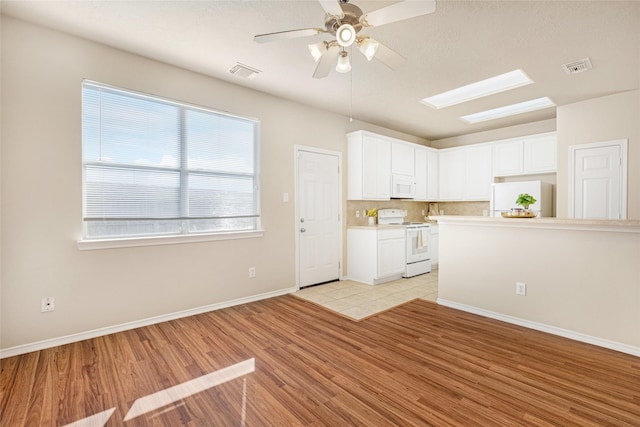 kitchen featuring white cabinetry, white appliances, plenty of natural light, and light wood-type flooring